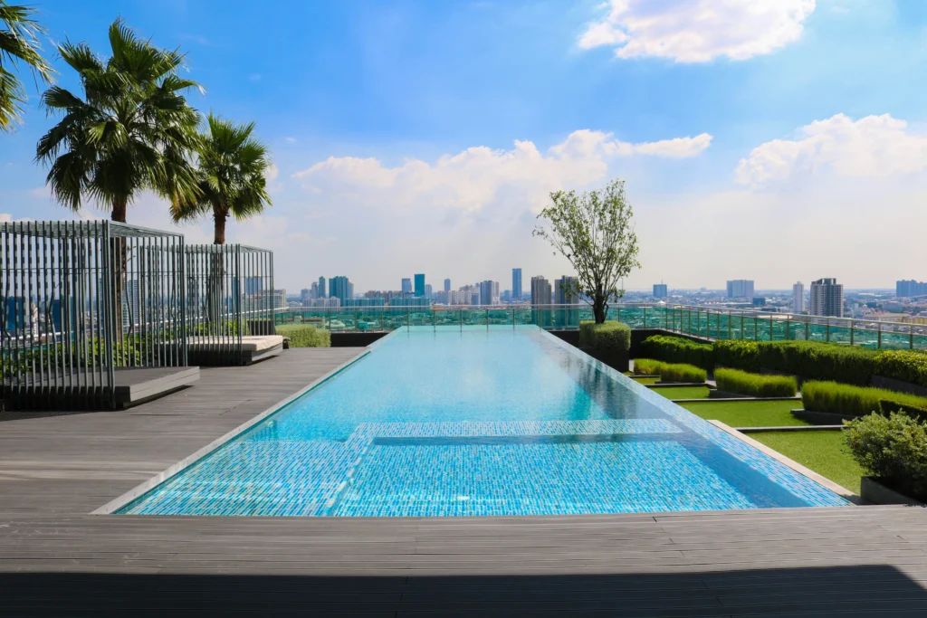 Modern swimming pool with lounge seating, landscaped deck, and outdoor leisure area at a premium apartment in Bhubaneswar by Saini Properties.